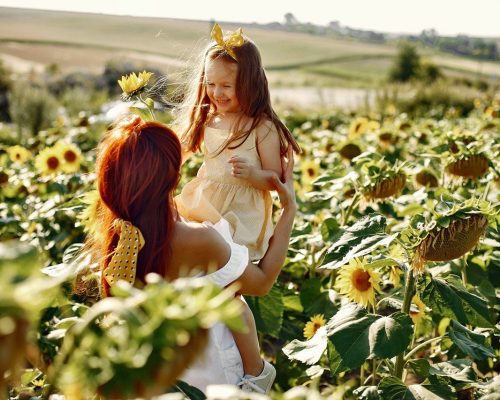 Mother with daughyer in a field. Sunflowers field. Family in a cute clothes