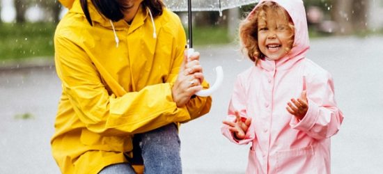 Mother with daughter walking in the rain under the umbrella Mother with daughter walking in the rain under the umbrella