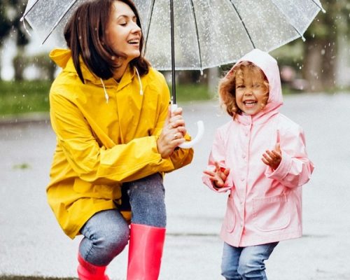 Mother with daughter walking in the rain under the umbrella Mother with daughter walking in the rain under the umbrella