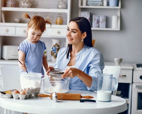 Family in a kitchen. Beautiful mother with little daughter. Woman in a blue shirt